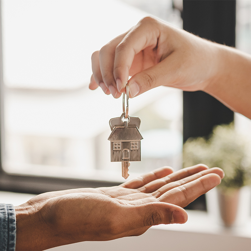 Real estate agent handing over house keys, representing Wedgewood Homes' seller rate buydown program for homebuyers