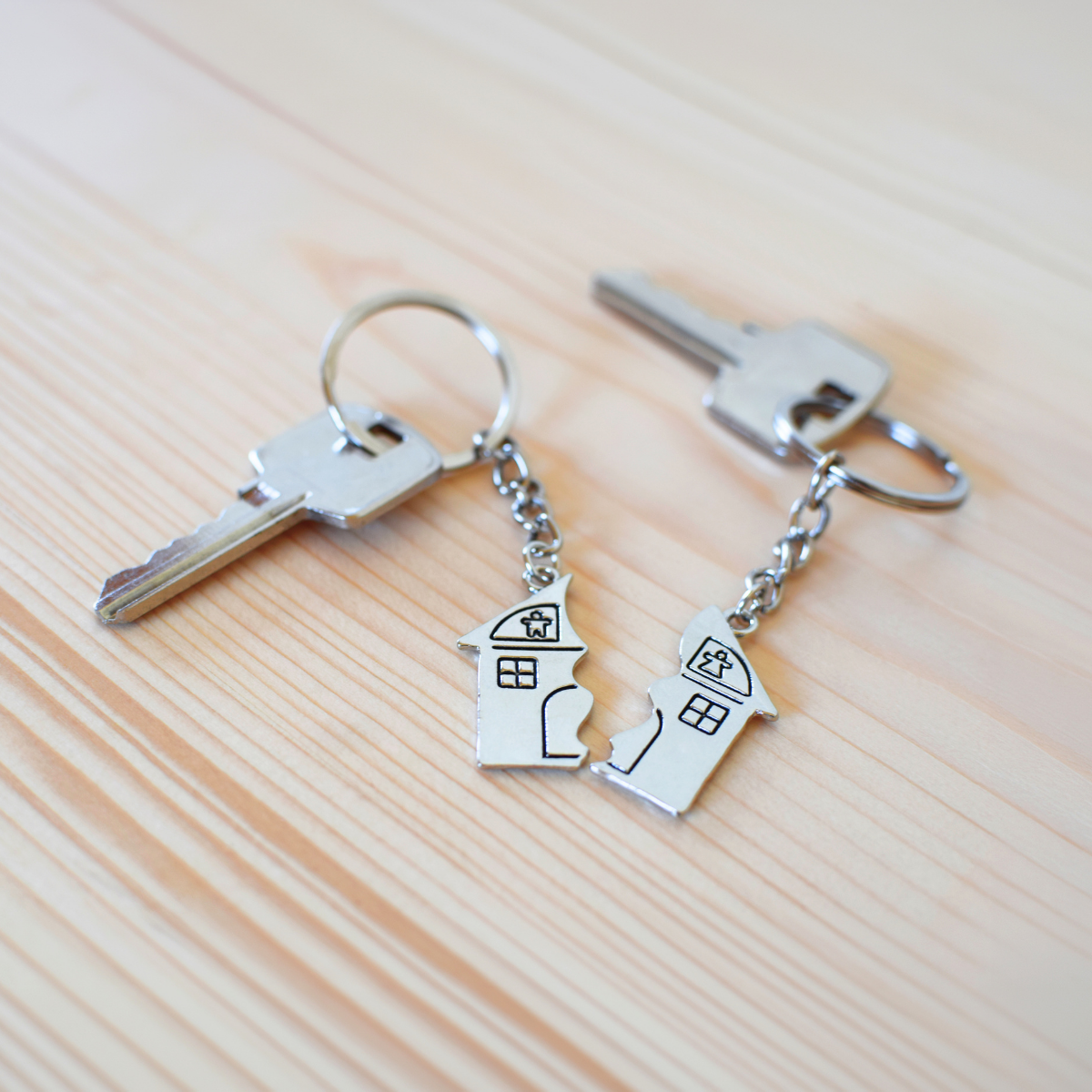 Two keychains with a broken house charm split in two — representing selling a house during divorce