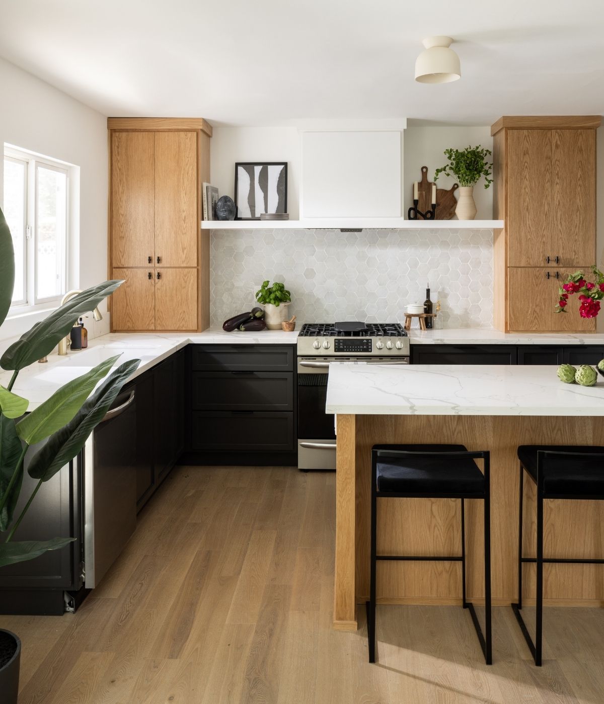 Maverick Design renovated kitchen featuring BuildDirect engineered hardwood flooring with two-tone oak and black cabinetry and marble countertops